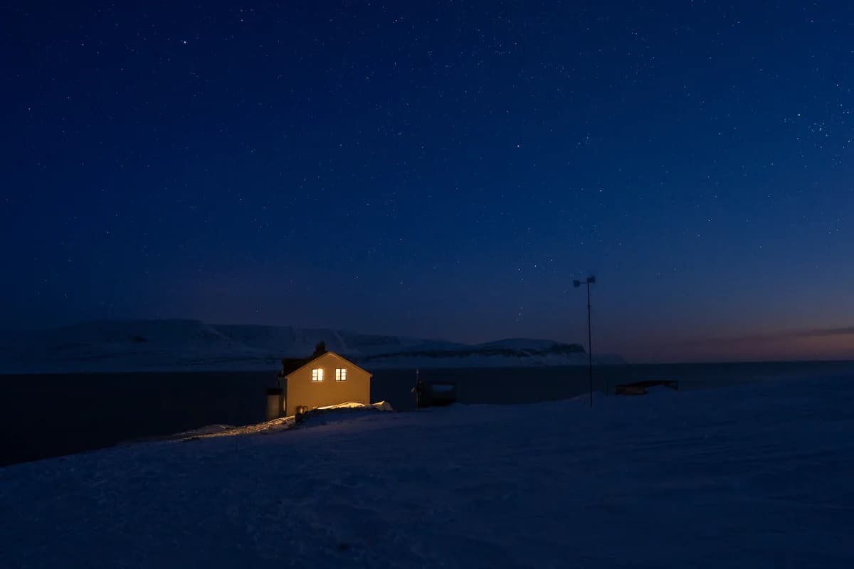 Upplyst stuga under en stjärnklar himmel