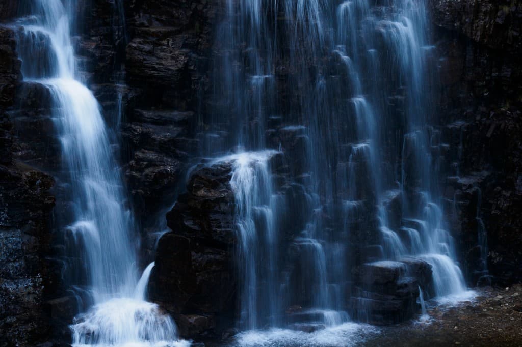 Vattenfall i blåtonat ljus mot mörk klippvägg — Rondane nationalpark
