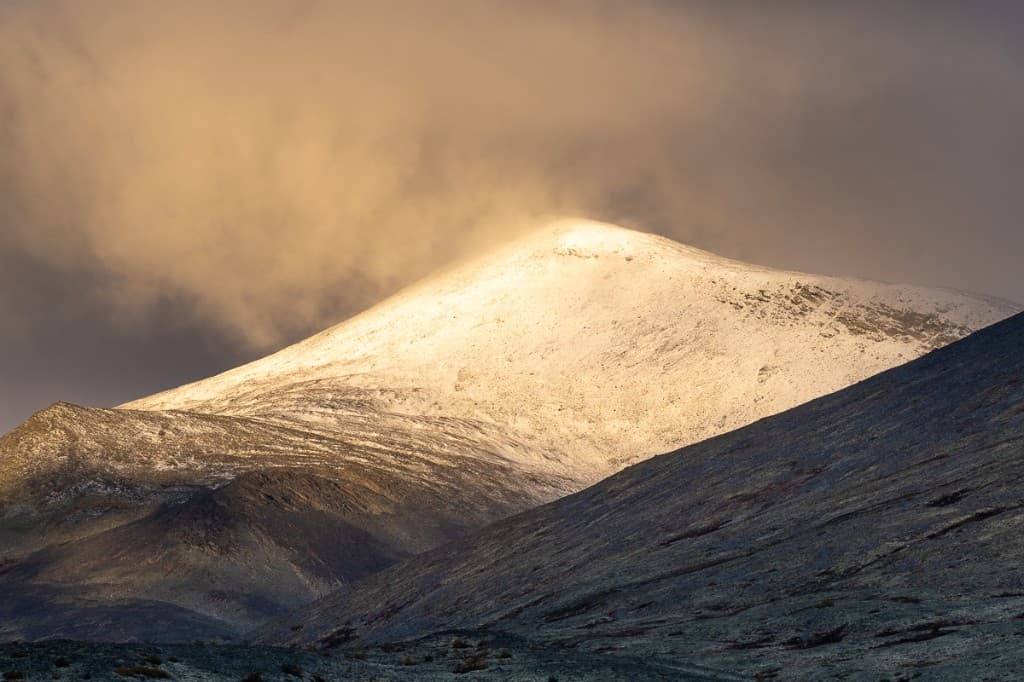 Snötäckt bergstapp i dramatiskt gyllene ljus — Rondane nationalpark