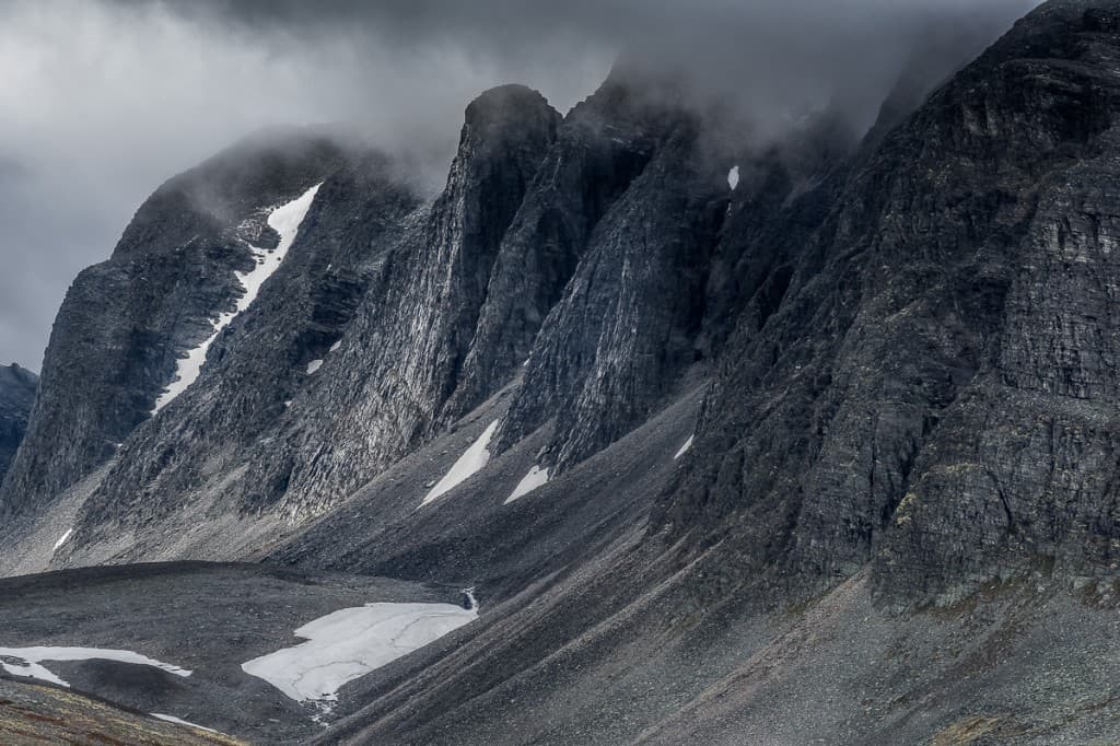 Dramatiska klippformationer och snöfläckar under mörka moln — Rondane nationalpark