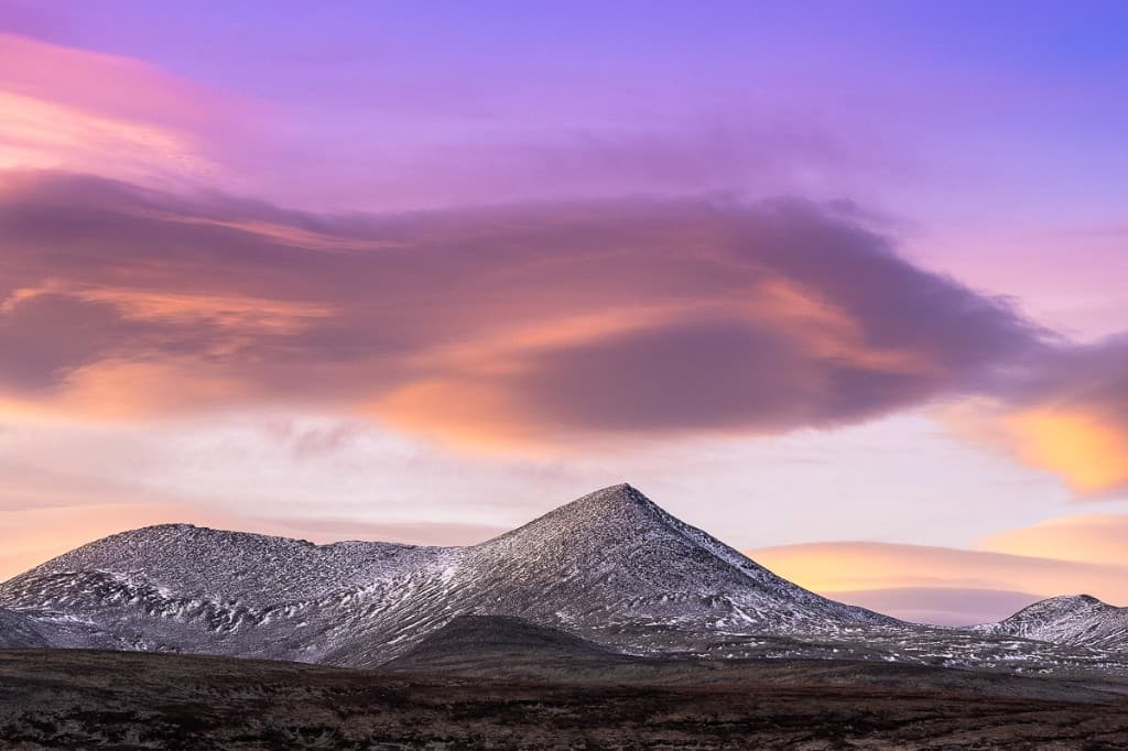 Snötäckt berg mot dramatisk lila och rosa solnedgångshimmel — Rondane nationalpark